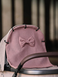 Waffle pram curtain with a bow in Old mauve attached to a stroller