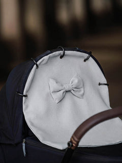 Light grey waffle stroller curtain with a bow attached to a pram