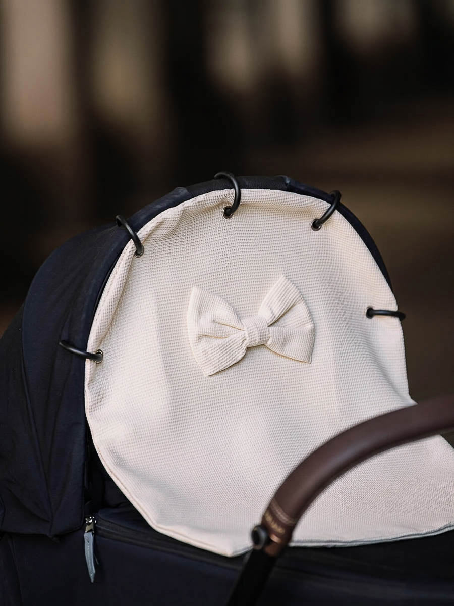 Off-white waffle stroller curtain with a bow attached to a pram hood