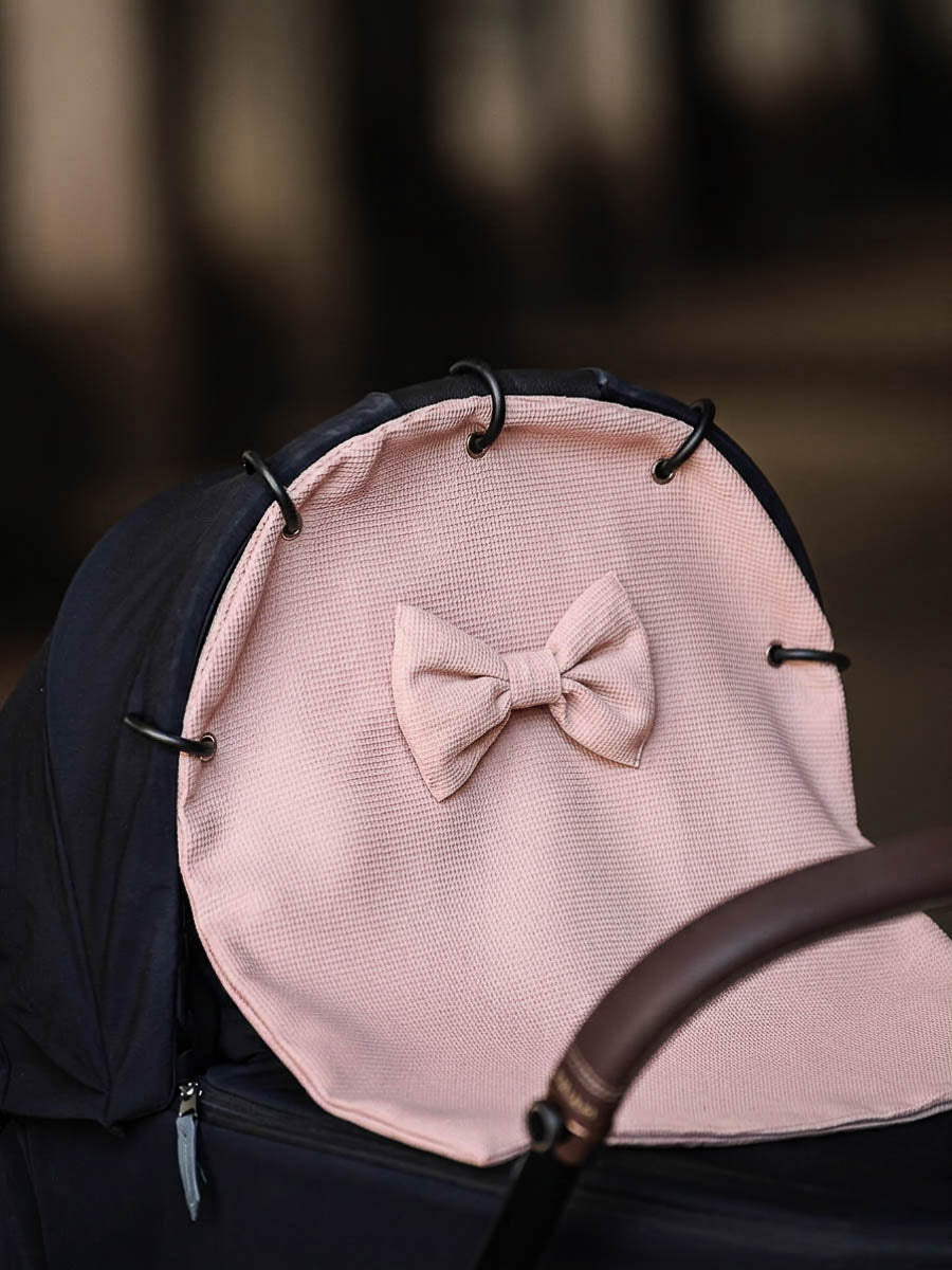 Pink waffle stroller curtain with a bow attached to a pram canopy