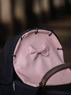 Dusty rose waffle pram curtain with a bow attached to a stroller